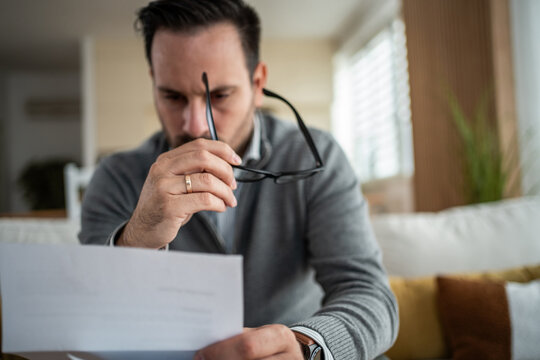 Stressed man reviewing home finances and documents - Powered by Adobe
