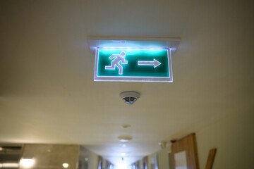 Arrow with running man indicates evacuation during emergency. Safety sign in hallway of hotel,...