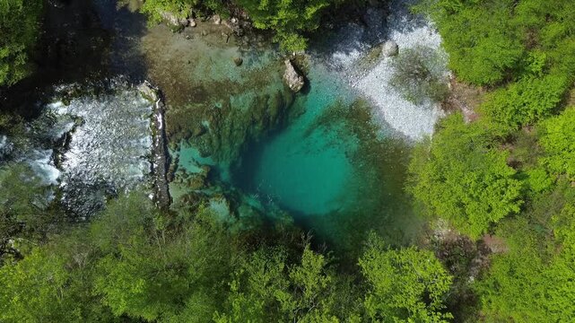 Aerial top view of turquoise spring water surrounded by lush green forest, Oko Skakavice in Montenegro, 4k