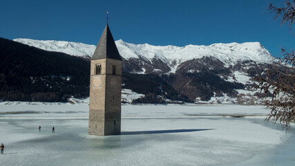 tower bell on frozen  lake resia during winter in south tyrol, italy