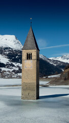 tower bell on frozen  lake resia during winter in south tyrol, italy