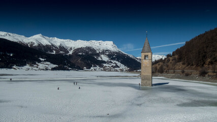 tower bell on frozen  lake resia during winter in south tyrol, italy