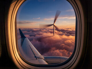 Aus dem Blick des Fensters eines Flugzeuges ist &uuml;ber den Wolken ein Windrad zu sehen.