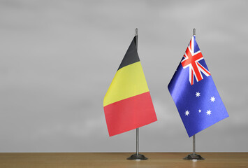 Tabletop flags of Belgium and Australia on stands on a gray blurred background