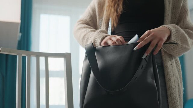 Caucasian Woman Organizing Documents And Wipes Into Black Tote On Glass Table, Sliding Envelope And Tissue Pack Into Inner Pocket, Focused Morning Ritual Before Commute, Blue Curtains And Neat