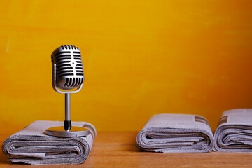 Retro microphone with newspaper on wooden table - announcement concept