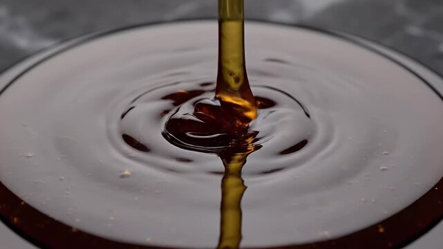 Honey Pouring Close-up - A close-up shot captures honey being poured, creating ripples and a glossy texture. The focus highlights the viscosity and golden hue of the liquid.