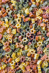 Fototapeta premium Background of colorful uncooked vegetable-flavored pasta,in the shape of a star, astronaut, and spaceships.Pasta made for children.