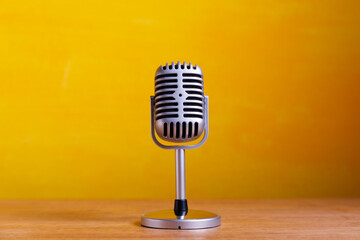 Retro Microphone on wooden table with yellow wall background