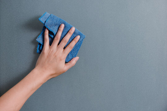 Hand and blue rag cleaning dark glass door