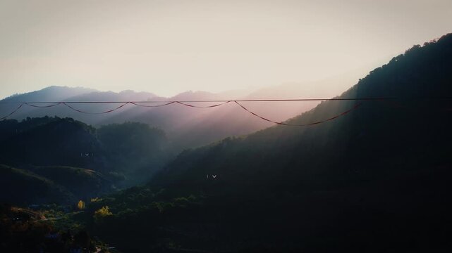 Sunrise paints the mountains as she finds balance on the fragile line above