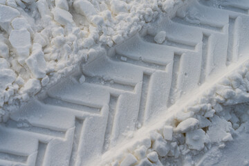 Car tire tracks in the snow. Winter weather. Rhythmic linear patterns and winter texture on snow. Artificial snow texture. Wide panoramic texture for background and design. Close-up view from above.