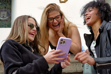 Diverse friends laughing and sharing content on smartphone