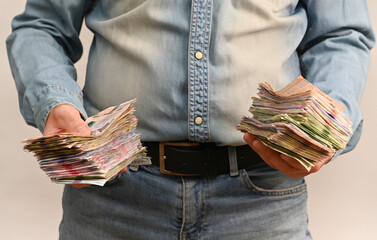 Two hands tightly hold a large bundle of Ukrainian banknotes, showing abundance of cash and strong financial theme. the concept of using cash in Ukraine, corruption and bribery.