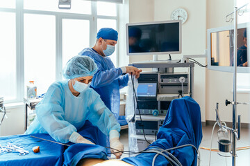 Surgeons preparing laparoscopic equipment during gynecological operation in hospital