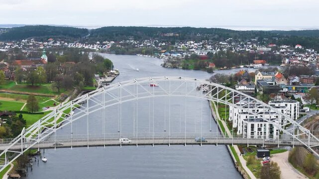 centered white steel arch bridge glomma river cars parks historic buildings apartments stretch across fredrikstad norway drone shot aerial view urban infrastructure vehicles 