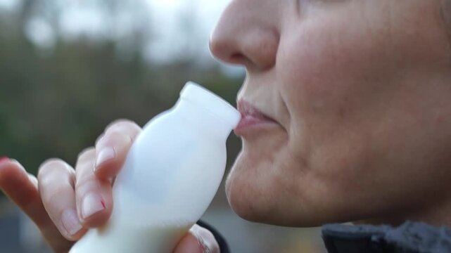 A detailed close-up shot of a person consuming a beverage from a small plastic bottle. The footage serves as a visual metaphor for the ingestion of microplastics 