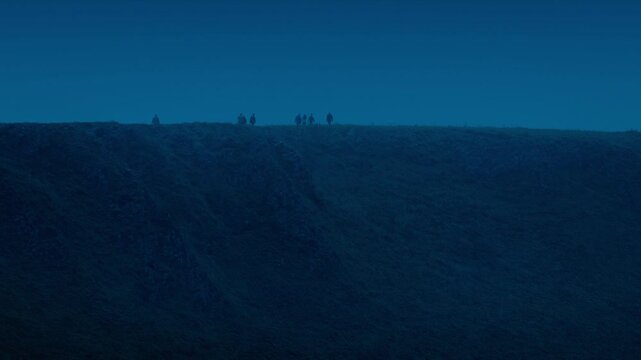 People Walking Along Hilltop In The Evening
