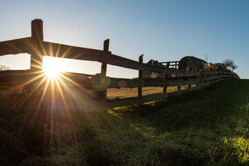 Zachodzące słońce uchwycone przez drewniany płot na wsi © Magdalena