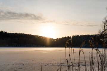 Frozen lake water. A bright sunset on a winter pond. Breathtaking winter landscape.