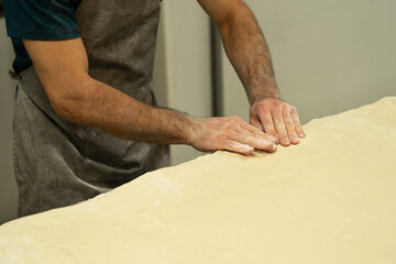 Close-up of baker’s hands shaping soft dough on worktable, tactile artisanal baking process and handmade food preparation.
