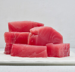 A stack of raw tuna pieces on a white board