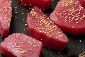 Raw tuna pieces in sesame seeds on a cutting board