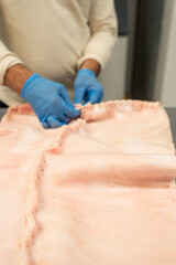 Naklejka premium Close-up of pork skin being stitched by chef, classic, lechona, lechón and cochinillo preparation method.