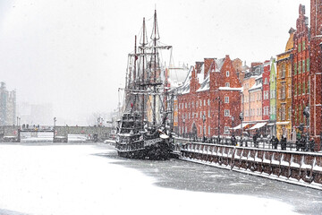 Beautiful ancient sail ship moored on the embankment of frozen Motlawa river in Gdansk