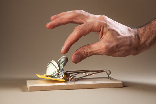 Close-up of man's hand putting money into mousetrap