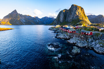 Sunrise over Hamn&oslash;y, Lofoten Islands, Northern Norway, with traditional red houses and dramatic mountains along the coastline.