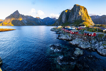 Sunrise over Hamn&oslash;y, Lofoten Islands, Northern Norway, with traditional red houses and dramatic mountains along the coastline.