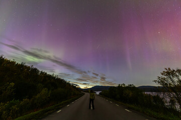 Northern lights in Kiruna, Sweden, reflecting on calm water in September with stars and forest in the background.