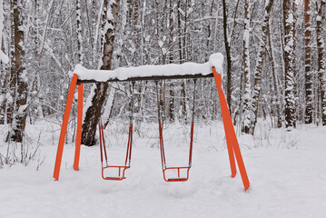 Hanging swing in a snowy forest park