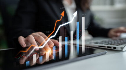 A business professional engages with digital data on a tablet, analyzing financial trends represented by colorful graphs and charts in a modern office setting. Scalp