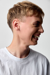 Naklejka premium Smiling boy, laughing face, joyful expression, casual white shirt, youth happiness, candid moment, playful mood, studio lighting, head turn, cheerful energy, showcasing carefree youth and bright