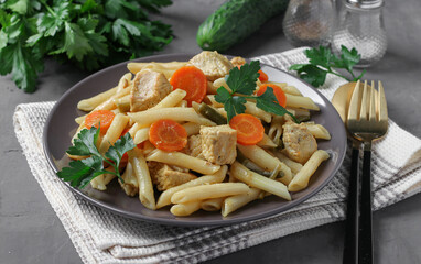 Penne pasta with turkey fillet and vegetables on gray plate