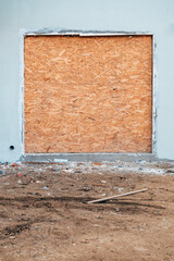 Boarded up doorway with plywood in unfinished construction site