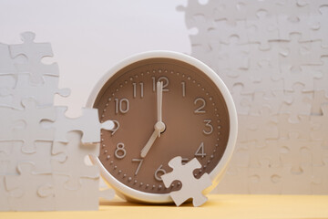 Alarm сlock surrounded by white jigsaw puzzle pieces. Time management concept.