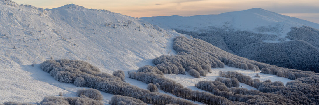 Frozen winter morning on Halicz peak in the Bieszczady Mountains. Snow-covered ridges, icy summit cross and clear sky along the popular Tarnica Halicz Rozsypaniec hiking loop.

