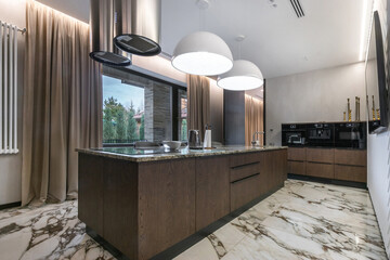 Stylish kitchen with a large island with marble countertops, elegant cabinets and modern lighting....