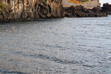 Mooring buoys floating in coastal waters marking designated boat mooring and anchorage areas near a rocky shoreline