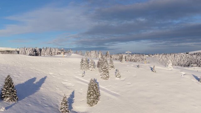 Panorama invernale aereo con neve ripreso da drone sopra Passo Coe sull'Alpe Cimbra di Folgaria nelle Alpi del Trentino-Alto Adige in Italia mentre i cannoni sparano neve