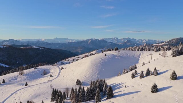 Panorama invernale aereo con neve ripreso da drone sopra Passo Coe sull'Alpe Cimbra di Folgaria nelle Alpi del Trentino-Alto Adige in Italia mentre i cannoni sparano neve