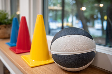 Colorful traffic cones and basketball on wooden windowsill in preschool or kindergarten classroom