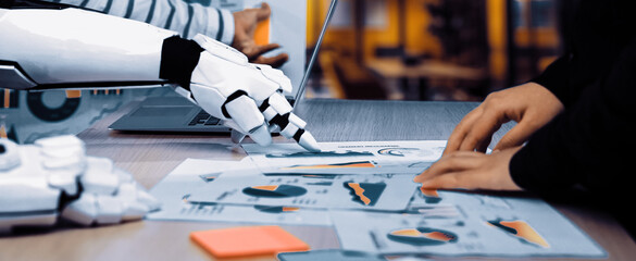 A futuristic robot collaborates with a human in an office setting, analyzing charts and data....