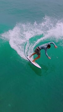Male Surfer Riding Turquoise Wave Off Bali Coastline Captured By Drone, Longboard Carving Through Barrel,vertical video