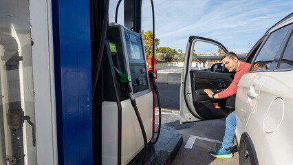 Man exiting car at gas station refueling