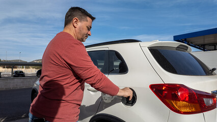 Man refueling white car at gas station pump