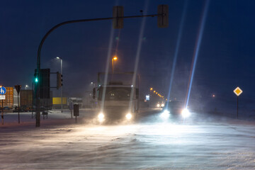 Extreme winter weather night with heavy snowstorm strong wind icy road surface truck  cars driving blizzard bright headlights cutting low visibility. Dangerous urban traffic conditions Germany